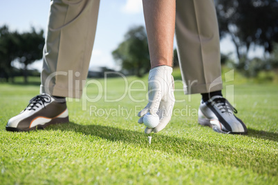 Golfer placing golf ball on tee