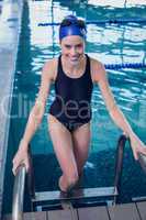 Fit swimmer smiling at camera getting out of the swimming pool