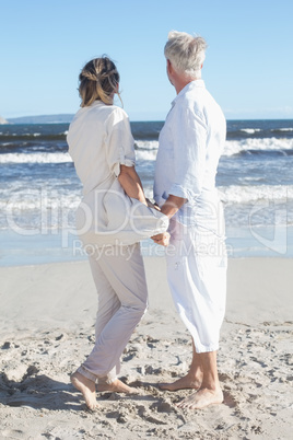 Couple on the beach looking out to sea holding hands