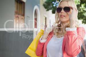 Pretty blonde in sunglasses holding shopping bags