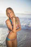 Happy blonde smiling at camera in bikini at the beach