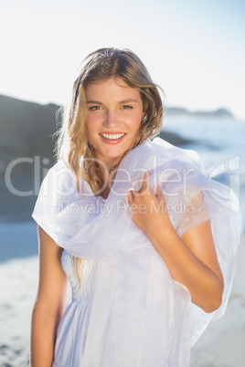 Beautiful smiling blonde in white sundress and scarf on the beac