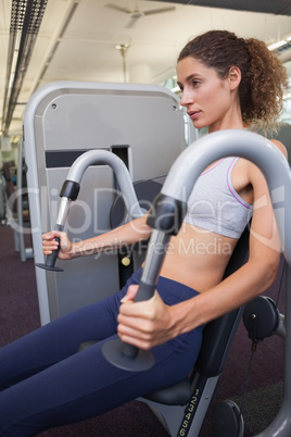 Fit woman using the weights machine for her arms