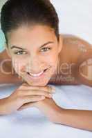 Smiling brunette lying on towel looking at camera