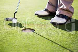 Golfer putting ball on the green