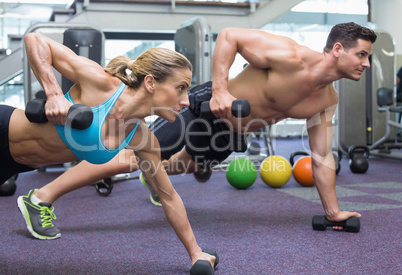 Bodybuilding man and woman holding dumbbells in plank position