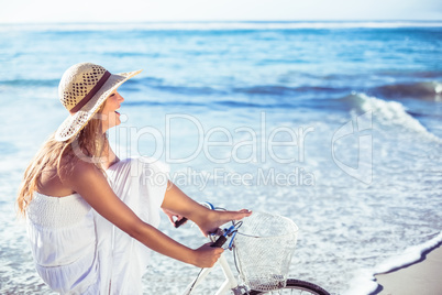 Beautiful blonde in white sundress on bike ride at the beach