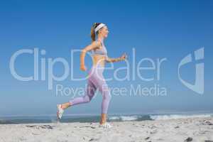 Sporty blonde on the beach jogging