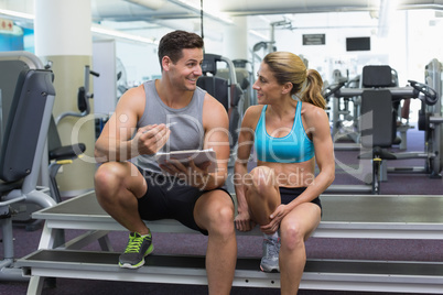 Female bodybuilder sitting with personal trainer talking