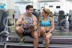 Female bodybuilder sitting with personal trainer talking