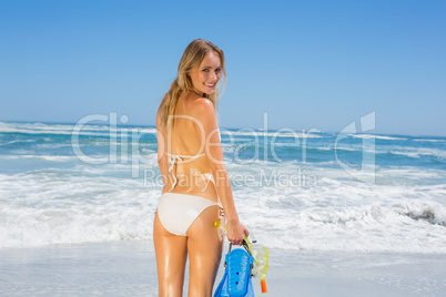Fit smiling woman in white bikini holding snorkeling gear on the