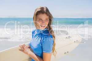 Fit smiling surfer girl on the beach with her surfboard