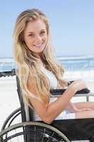 Wheelchair bound blonde smiling at the camera on the beach