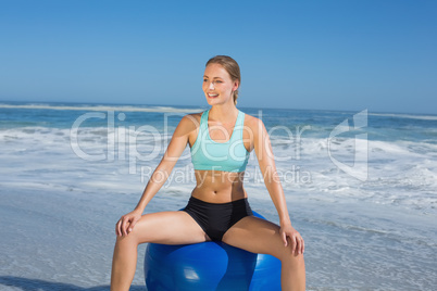 Fit woman sitting on exercise ball at the beach