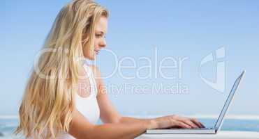 Pretty blonde using her laptop at the beach