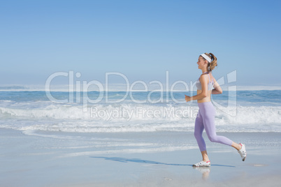 Sporty smiling blonde jogging on the beach