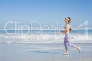 Sporty smiling blonde jogging on the beach