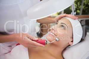 Peaceful brunette getting micro dermabrasion from beauty therapi