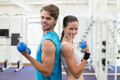 Fit couple exercising together with blue dumbbells