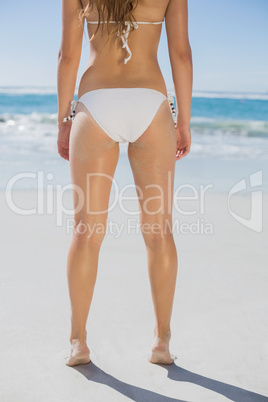 Rear view of fit woman in white bikini on beach