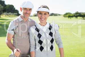 Golfing couple smiling at camera on the putting green