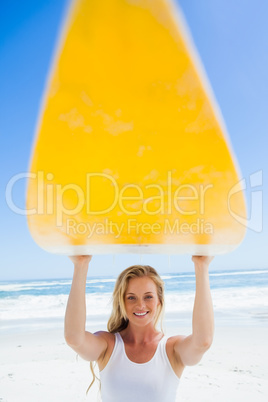 Blonde surfer holding her board smiling at camera