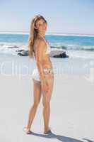 Smiling fit woman in white bikini on beach