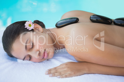 Relaxed brunette lying on towel having a hot stone massage