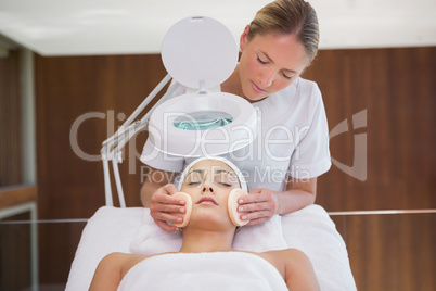 Peaceful brunette getting facial from beauty therapist