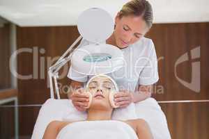 Peaceful brunette getting facial from beauty therapist