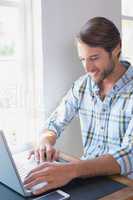 Handsome man sitting at table using laptop