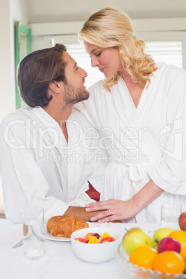 Cute couple in bathrobes having breakfast together