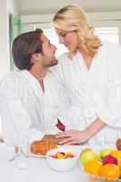 Cute couple in bathrobes having breakfast together