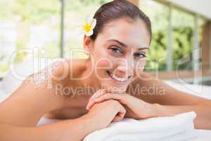 Beautiful smiling brunette lying on massage table with salt scru