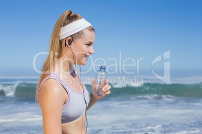 Sporty blonde on the beach drinking water