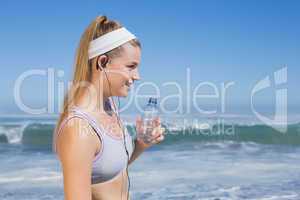 Sporty blonde on the beach drinking water