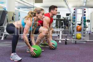 Bodybuilding man and woman lifting medicine balls doing squats
