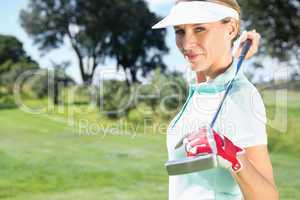 Female golfer standing holding her club smiling at camera