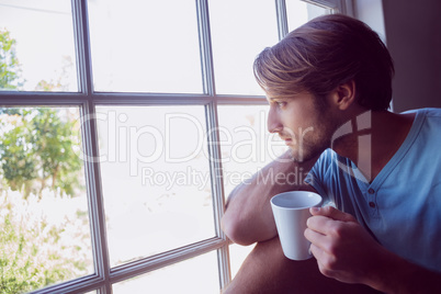 Thoughtful man sitting by the window having coffee