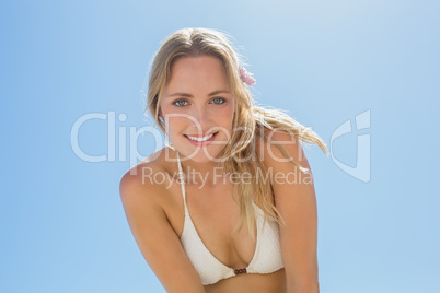 Beautiful blonde in white bikini smiling at camera on the beach