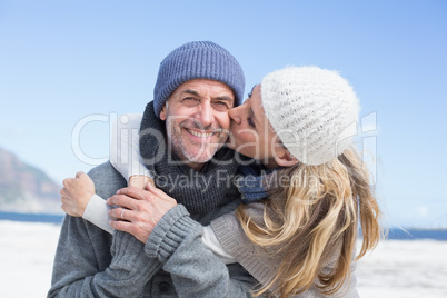 Attractive couple hugging on the beach in warm clothing