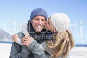 Attractive couple hugging on the beach in warm clothing