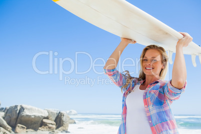 Blonde surfer holding her board smiling at camera