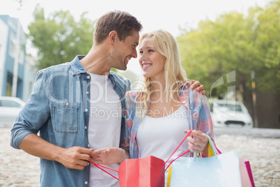 Hip young couple looking at their shopping bags Hip young couple looking at their shopping bags