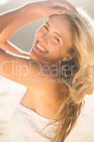 Blonde in white dress smiling at camera on the beach