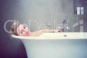 Serene blonde lying in the bath smiling at camera
