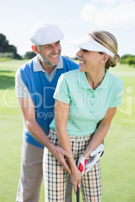 Golfing couple putting ball together smiling at camera each othe