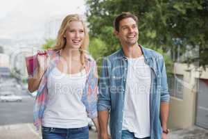 Hip young couple on shopping trip walking uphill