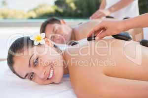 Attractive couple enjoying hot stone massage poolside