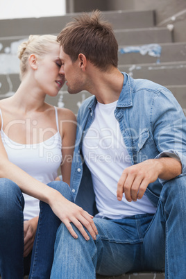 Hip young couple in denim sitting on steps about to kiss